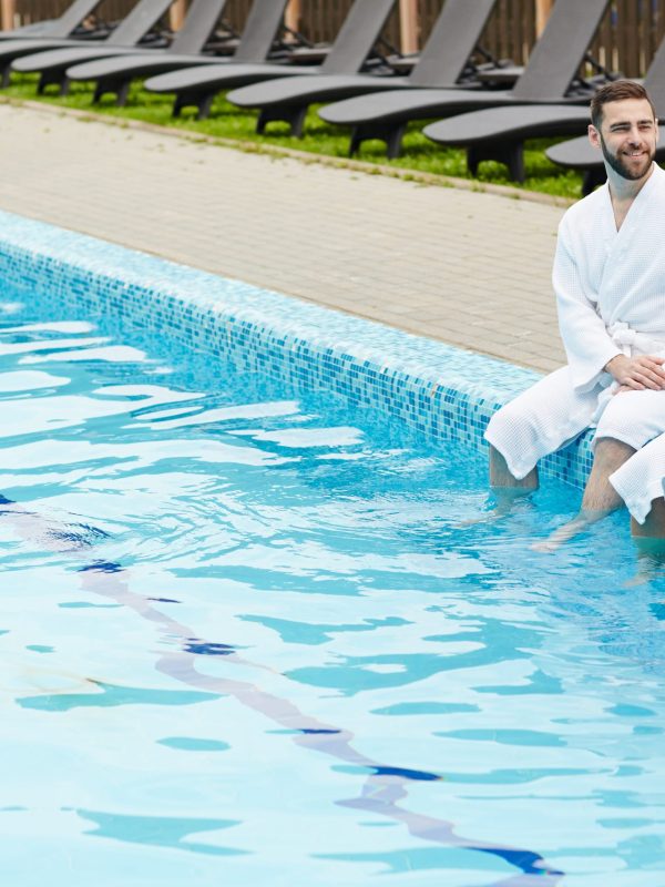 Carefree couple Restful young couple splashing water in swimming pool of spa resort not far from hotel
